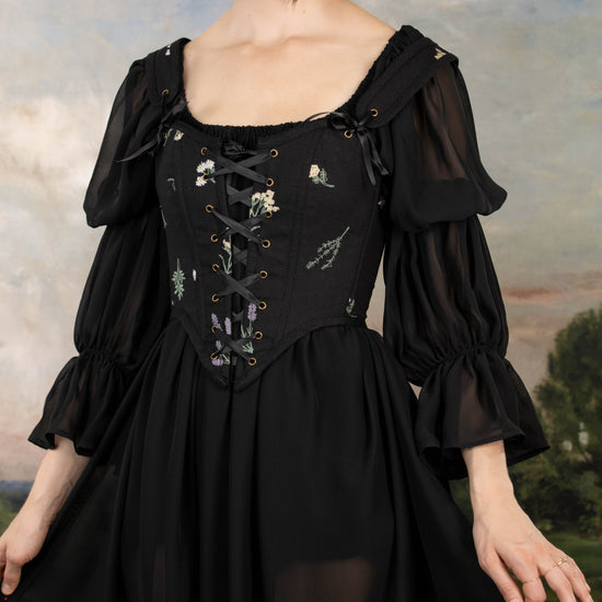 model wearing black floral corset over sheer black chemise dress