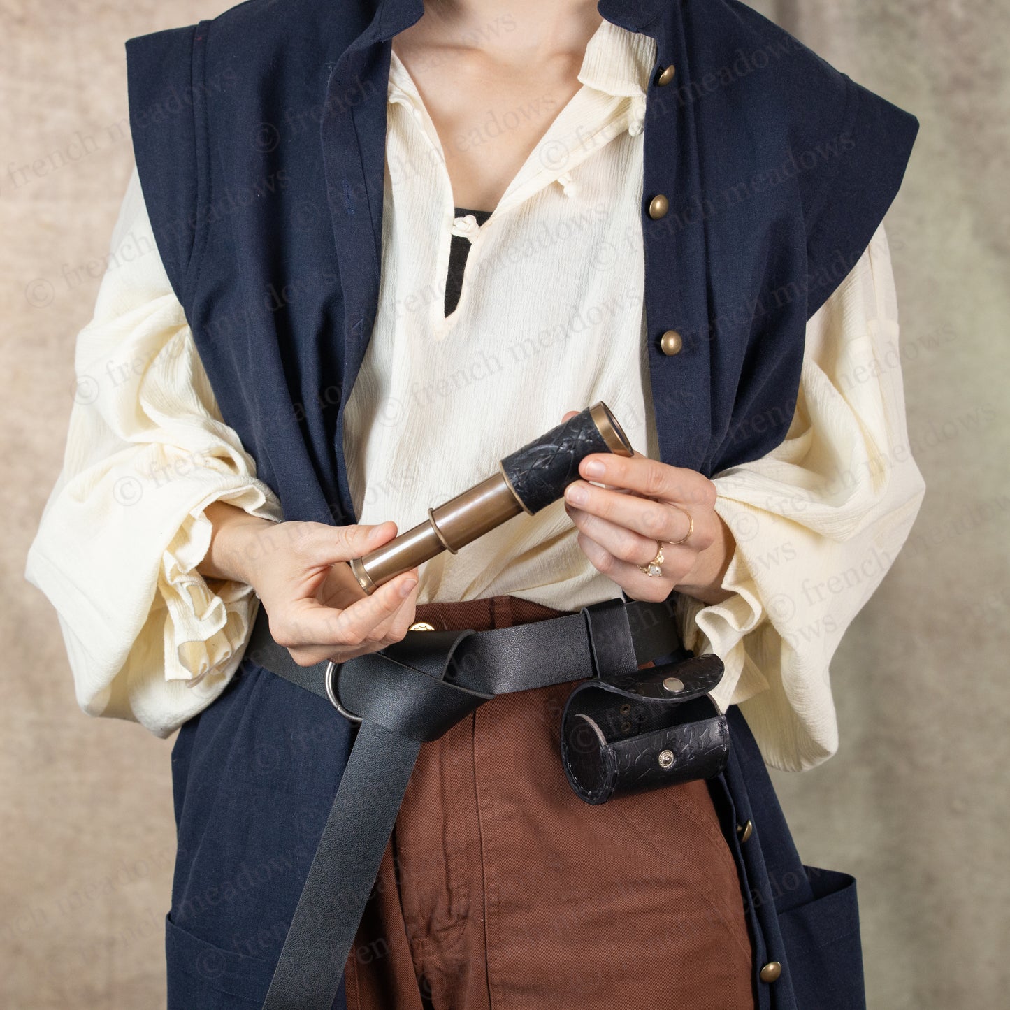 model dressed in pirate costume holding black spyglass telescope in both hands