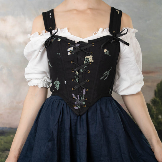 model wearing black floral corset top with navy blue linen skirt and peasant blouse off the shoulders