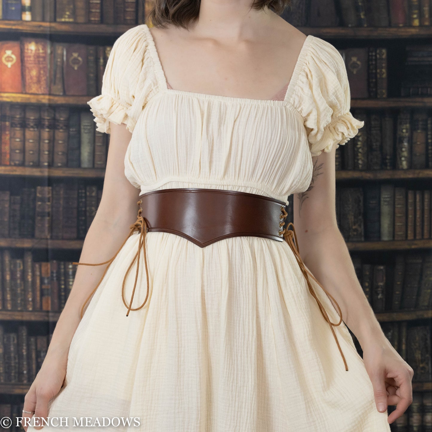 model wearing brown leather waist harness over cream colored renaissance dress