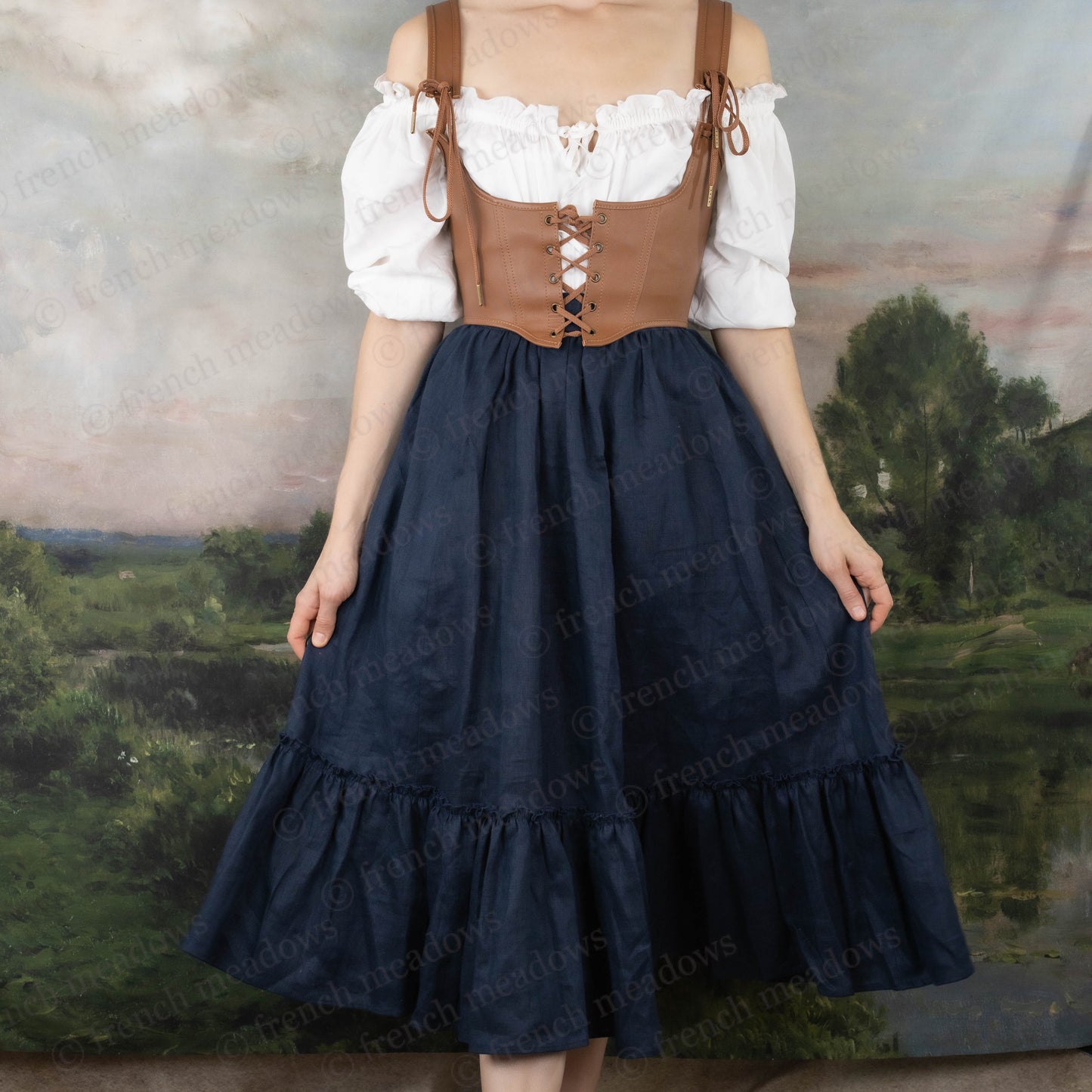 model wearing white cotton blouse under a navy blue skirt and brown leather corset