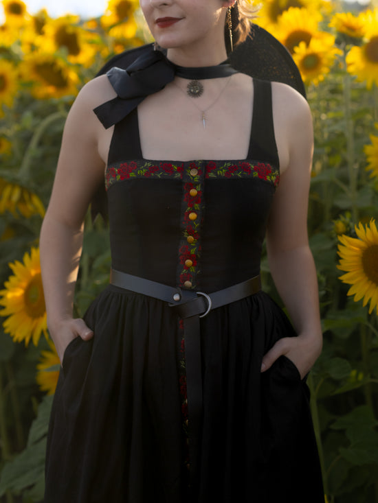 close up of model wearing black dress with red floral slavic ribbon detail