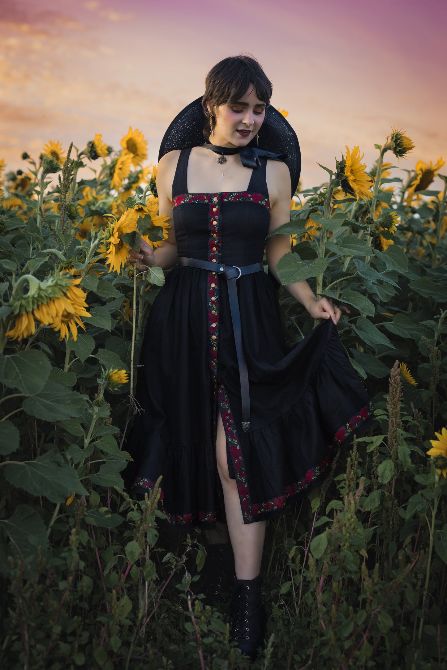 model wearing black ribbon dress in a field of sunflowers, dressed in a witch aesthetic